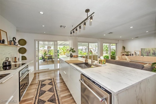 kitchen with a sink, white cabinets, stainless steel dishwasher, and light countertops