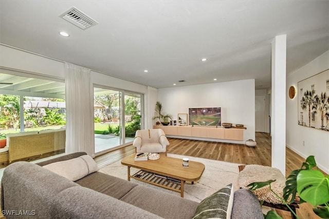 living room featuring baseboards, recessed lighting, visible vents, and light wood-style floors