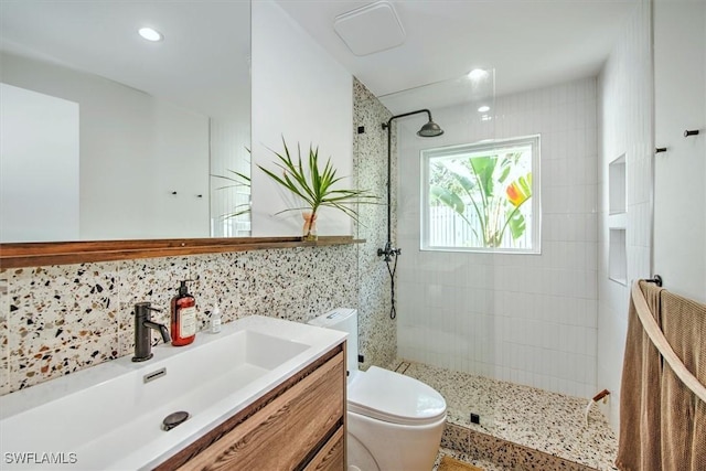 bathroom featuring tile walls, tasteful backsplash, toilet, vanity, and a walk in shower