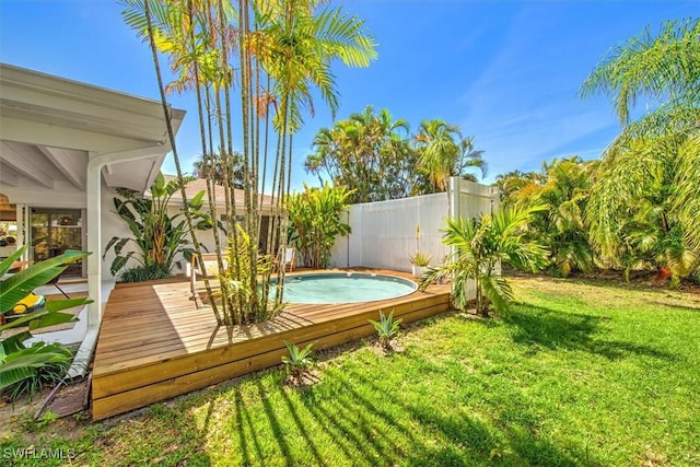 view of pool with a deck, a lawn, and a fenced backyard