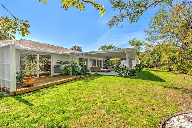 rear view of house featuring ceiling fan, a deck, and a lawn