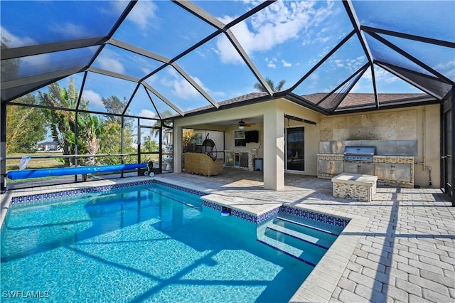 pool featuring ceiling fan, glass enclosure, exterior kitchen, and a patio area