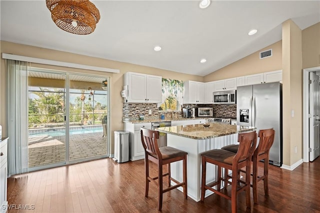 kitchen with stainless steel appliances, visible vents, white cabinets, a kitchen island, and a kitchen breakfast bar