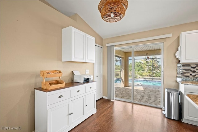 doorway to outside featuring lofted ceiling, dark wood-style flooring, and baseboards