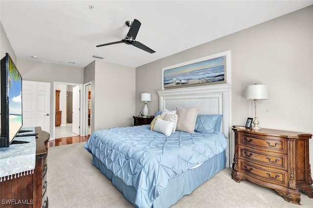 bedroom with ensuite bathroom, ceiling fan, visible vents, and light colored carpet