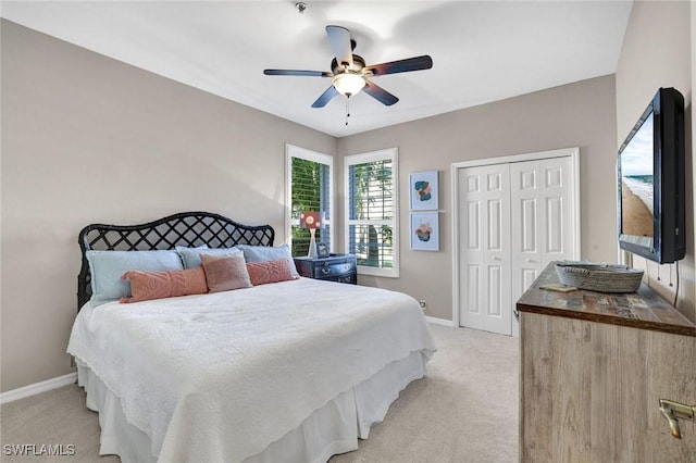 bedroom with a closet, light colored carpet, and baseboards