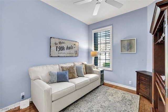 living room with a ceiling fan, baseboards, and wood finished floors