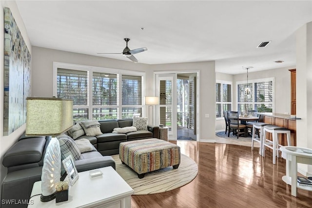 living room with a ceiling fan, a wealth of natural light, visible vents, and wood finished floors