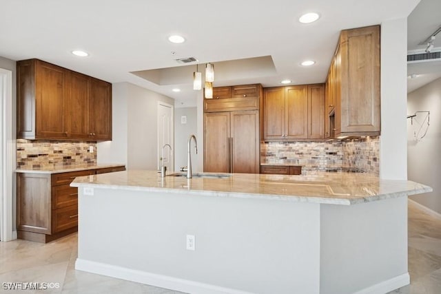 kitchen with paneled fridge, a peninsula, a sink, and light stone countertops