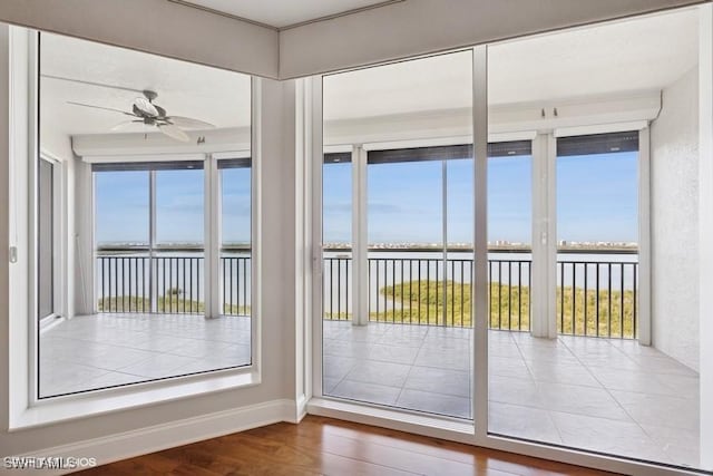 unfurnished sunroom featuring a water view and ceiling fan