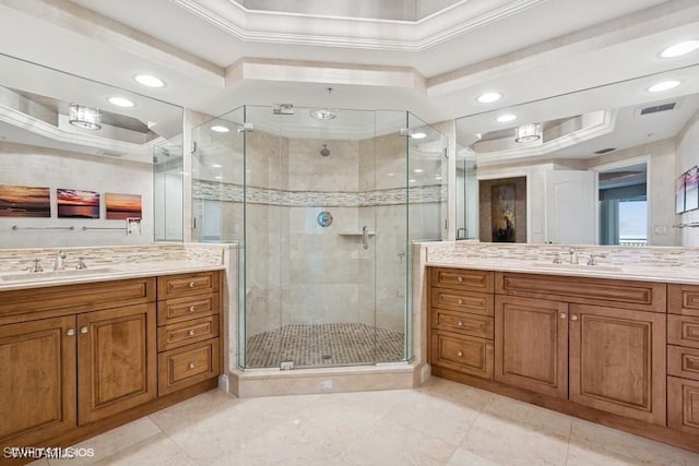 full bath with a raised ceiling, two vanities, a sink, and a shower stall