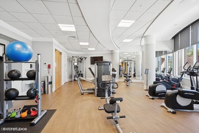 workout area featuring crown molding, visible vents, light wood-type flooring, a drop ceiling, and baseboards