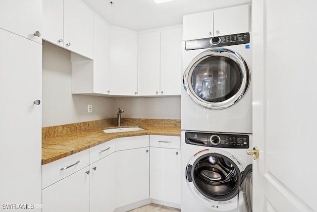 washroom featuring stacked washer and dryer, a sink, and cabinet space