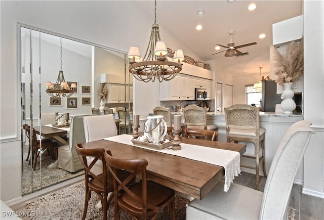 dining space with dark wood-style floors, high vaulted ceiling, ceiling fan with notable chandelier, and recessed lighting