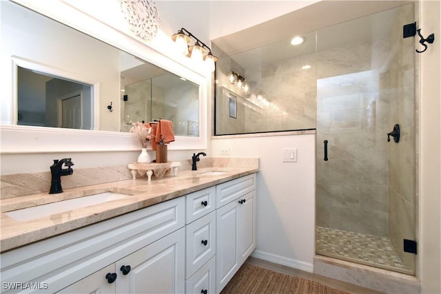 bathroom featuring a sink, a shower stall, baseboards, and double vanity