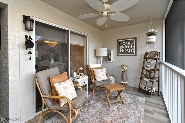 living area featuring ceiling fan, wood finished floors, and a textured wall