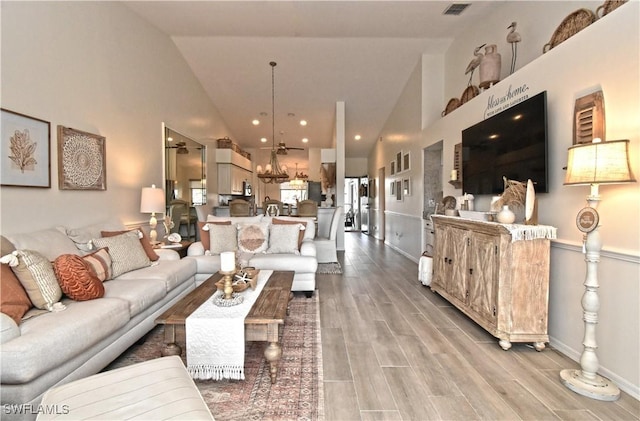 living room with wood finish floors, recessed lighting, visible vents, high vaulted ceiling, and baseboards