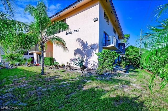 view of home's exterior featuring a yard, a balcony, and stucco siding