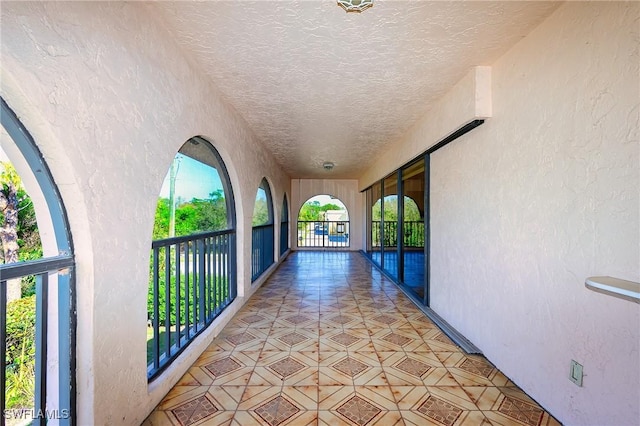 hall with a textured ceiling and a textured wall