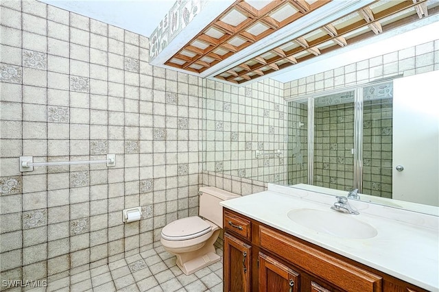 full bath with toilet, tile patterned floors, tile walls, and vanity