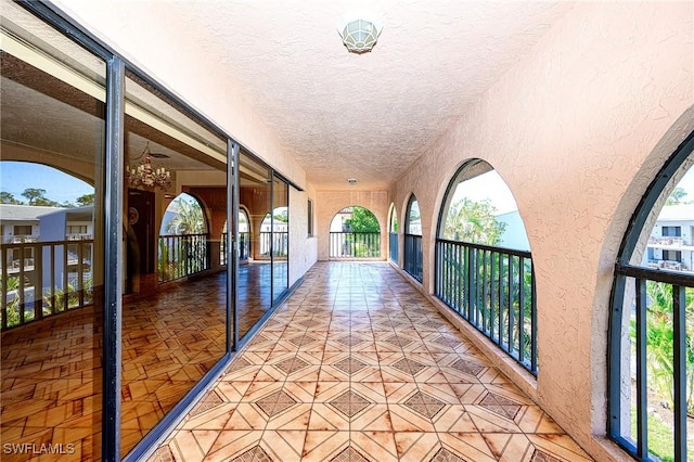 hall featuring a textured ceiling, a textured wall, and tile patterned flooring