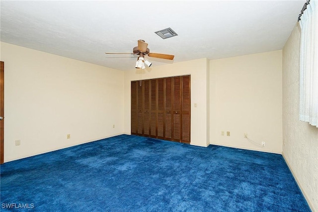 unfurnished bedroom with dark carpet, visible vents, and a ceiling fan