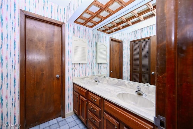 full bath with double vanity, wallpapered walls, baseboards, tile patterned flooring, and a sink