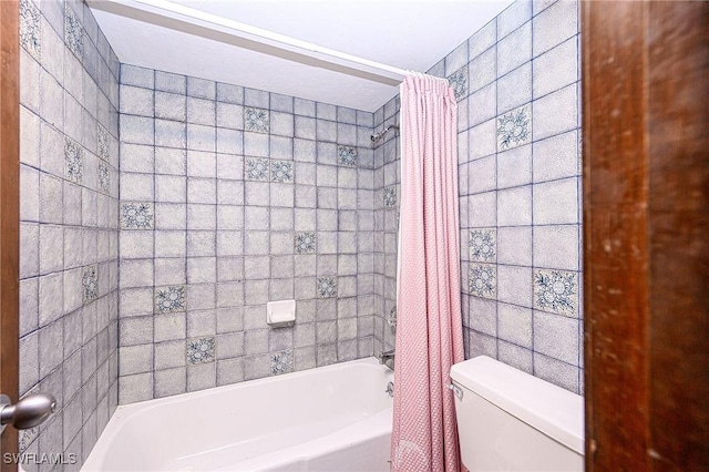 bathroom with toilet, tile walls, and shower / tub combo with curtain