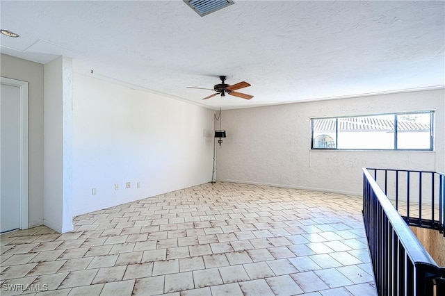 empty room featuring visible vents, a textured wall, a textured ceiling, and ceiling fan