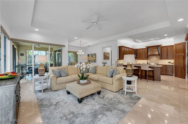 living room featuring recessed lighting, a raised ceiling, and ceiling fan with notable chandelier