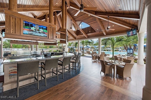 interior space featuring ceiling fan, wood finished floors, wood ceiling, and ornate columns