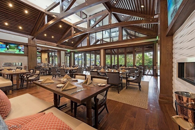 dining space with high vaulted ceiling, beam ceiling, and wood finished floors