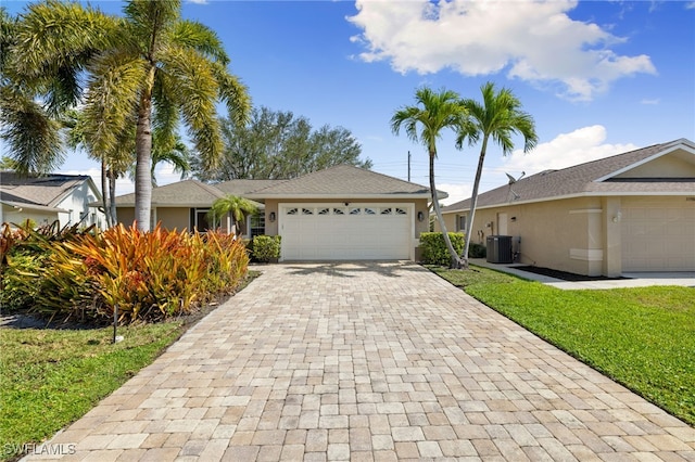 ranch-style house featuring stucco siding, cooling unit, an attached garage, and decorative driveway