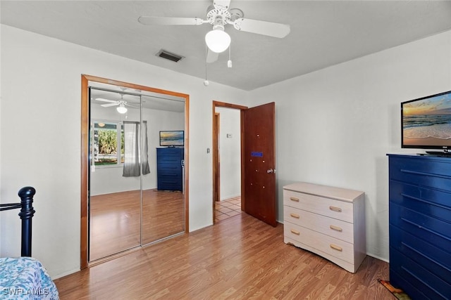 bedroom with light wood-style flooring, visible vents, ceiling fan, and a closet