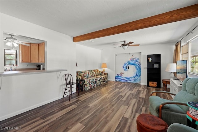 living area with beam ceiling, ceiling fan, a textured ceiling, wood finished floors, and baseboards