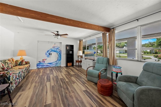 living area with a textured ceiling, beamed ceiling, wood finished floors, and baseboards