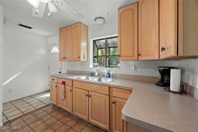 kitchen with tasteful backsplash, visible vents, light countertops, light brown cabinetry, and a sink