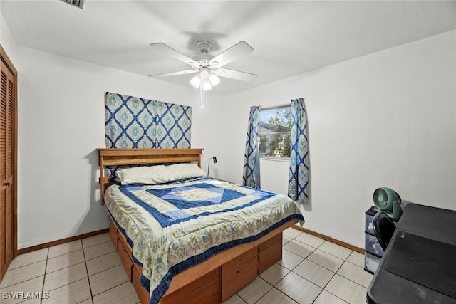 bedroom featuring light tile patterned floors, baseboards, a ceiling fan, and a closet