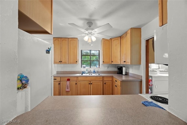 kitchen featuring ceiling fan, light countertops, a sink, and washer and dryer