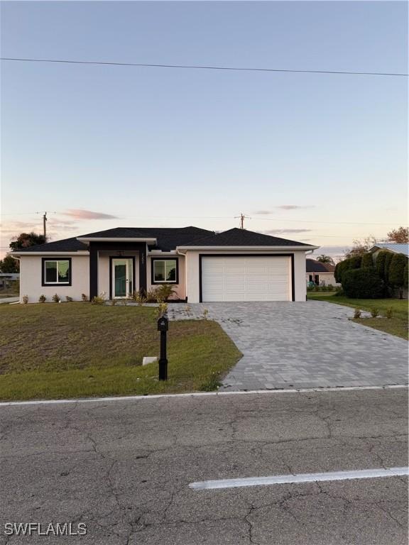 view of front of home featuring a garage, a front lawn, decorative driveway, and stucco siding