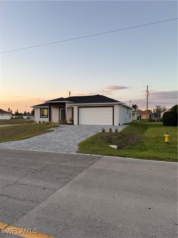 view of front of property featuring a garage, decorative driveway, and a front yard