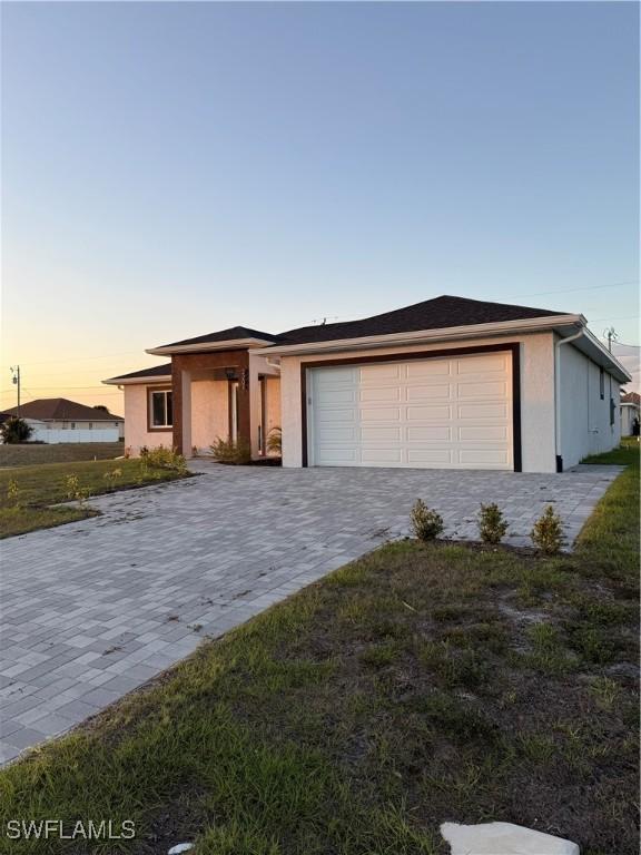 view of front of home featuring a yard, decorative driveway, an attached garage, and stucco siding