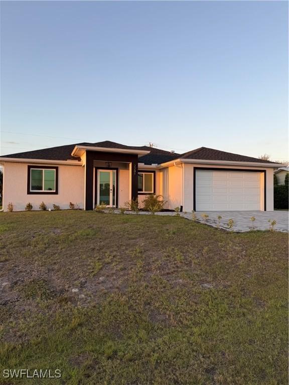 view of front of house featuring a front yard, driveway, an attached garage, and stucco siding