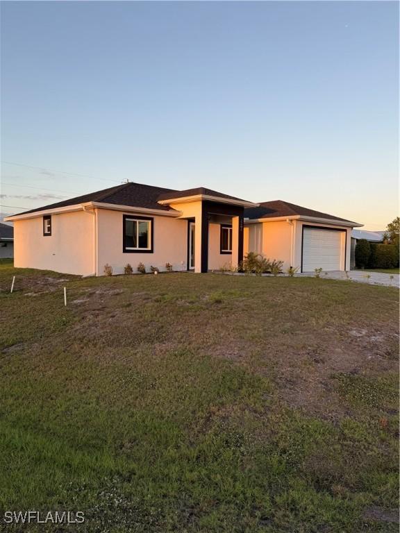 view of front of house featuring driveway, a front lawn, an attached garage, and stucco siding