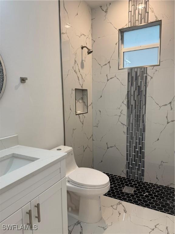 bathroom with a marble finish shower, vanity, toilet, and marble finish floor