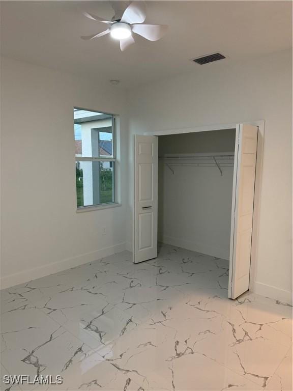 unfurnished bedroom featuring marble finish floor, a closet, visible vents, ceiling fan, and baseboards