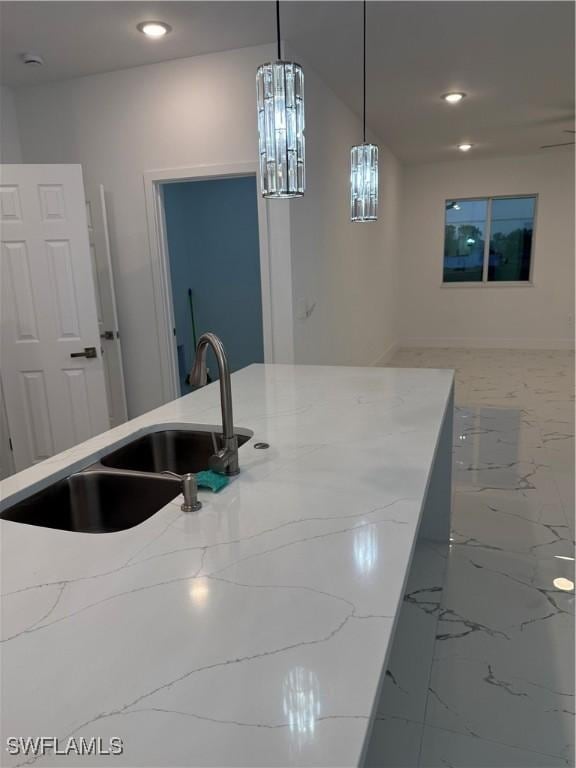 kitchen with light stone counters, recessed lighting, a sink, marble finish floor, and pendant lighting