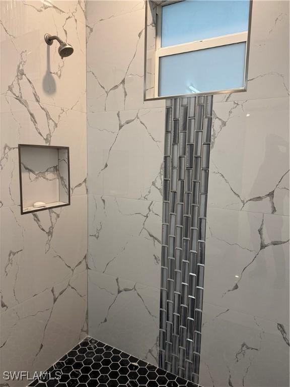 bathroom featuring a marble finish shower