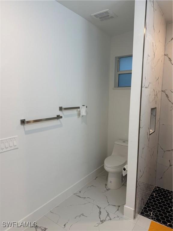 bathroom featuring toilet, visible vents, baseboards, marble finish floor, and a marble finish shower