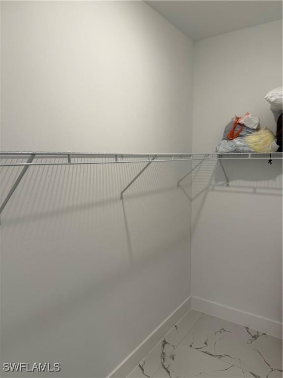 walk in closet featuring marble finish floor